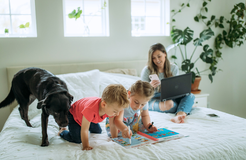 A woman who is distracted while working from home by her phone, children and dog. 