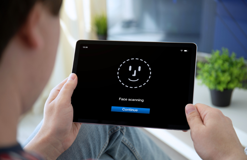 A man logging in by scanning his face. Passkeys and behavioral biometrics are the ideal protection system.