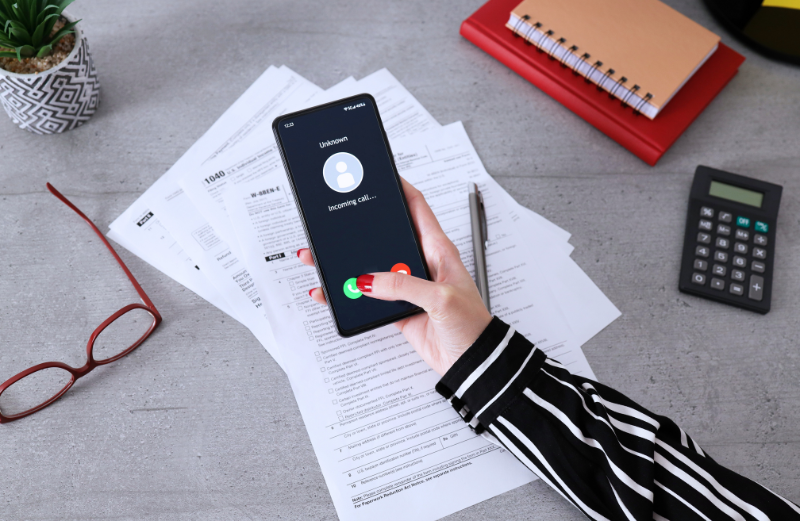 Ženská ruka drží mobil, na ktorom svieti prichádzajúci hovor. Freelanceri, ktorí sa usilujú o jasnú a konzistentnú komunikáciu s klientmi, si vybudujú dobrú reputáciu.
