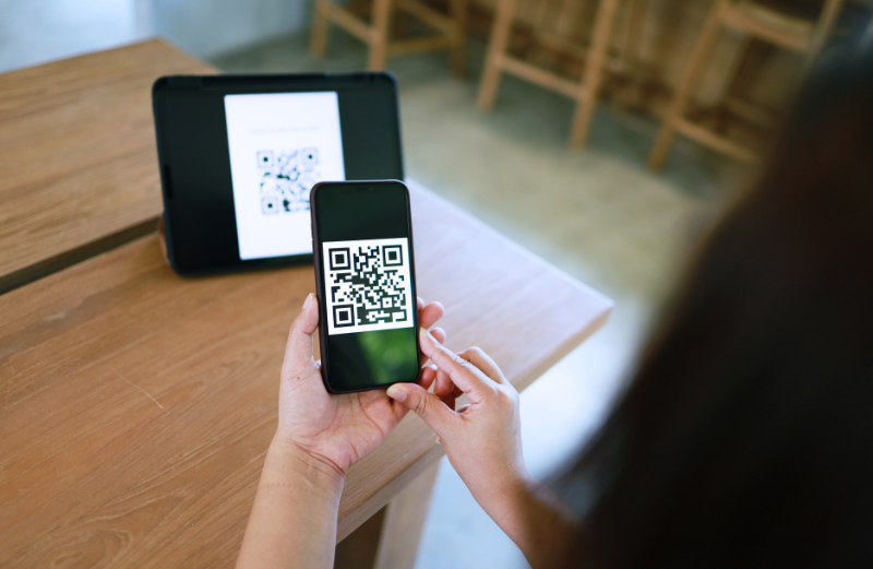 Osoba skenujúca QR kód z laptopu. Quishing je obľúbenou stratégiou kyberzločincov, pretože pri QR kódoch je menšia pravdepodobnosť, že budú označené za bezpečnostnú hrozbu.