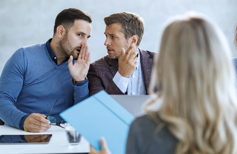 Male colleagues whisper about a female coworker.
